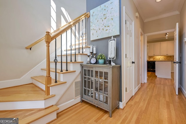 stairs with ornamental molding and hardwood / wood-style floors