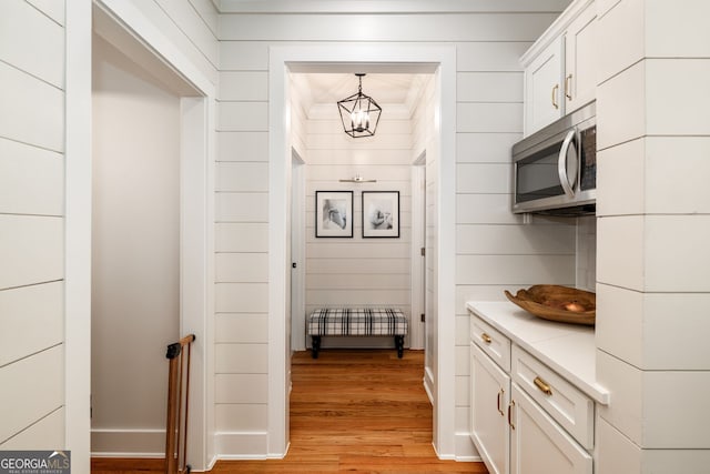 kitchen featuring light hardwood / wood-style floors, decorative light fixtures, white cabinets, and ornamental molding