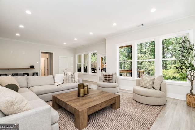 living room featuring plenty of natural light, ornamental molding, and light hardwood / wood-style floors