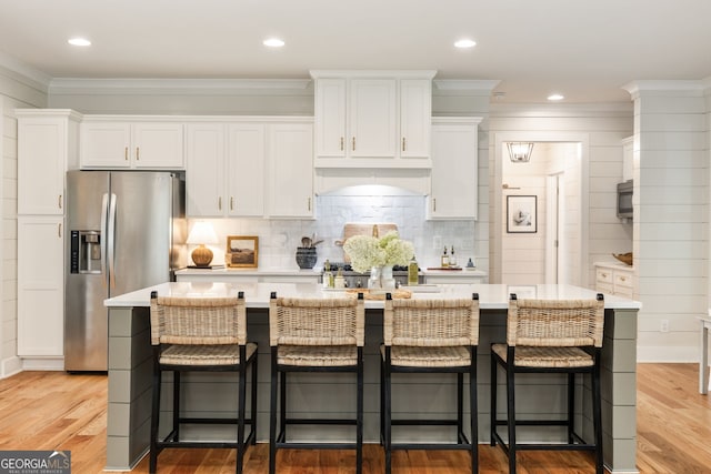 kitchen featuring a kitchen bar, wood-type flooring, and white cabinets