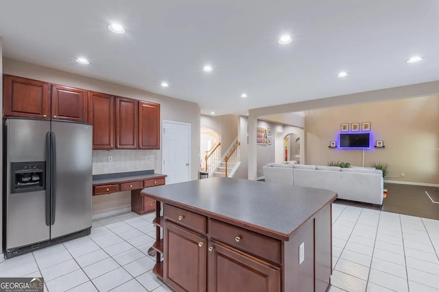 kitchen featuring stainless steel fridge with ice dispenser, a kitchen island, decorative backsplash, and light tile patterned floors