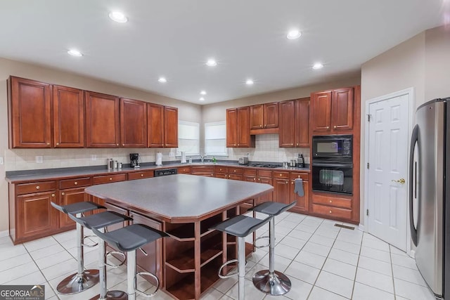 kitchen with black appliances, a kitchen island, tasteful backsplash, and light tile patterned floors