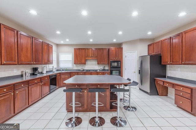 kitchen with a center island, black appliances, tasteful backsplash, and light tile patterned floors