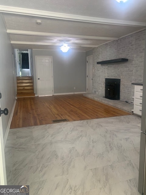 unfurnished living room with tile patterned floors, a fireplace, beamed ceiling, and brick wall