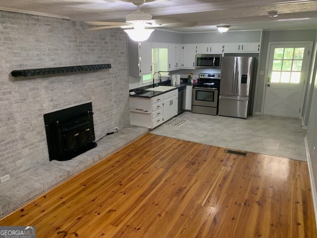 kitchen featuring a fireplace, brick wall, appliances with stainless steel finishes, and light tile patterned floors