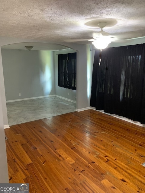 spare room featuring ceiling fan, wood-type flooring, and a textured ceiling