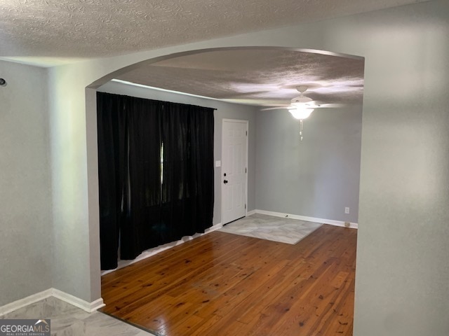 unfurnished room featuring ceiling fan, a textured ceiling, and wood-type flooring