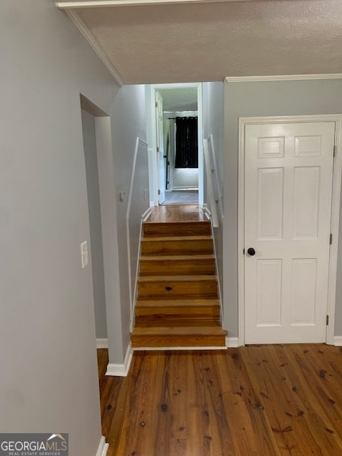 stairs with crown molding and hardwood / wood-style floors