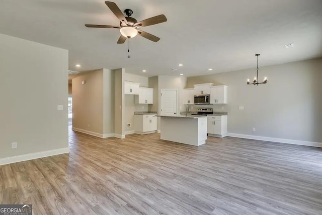 kitchen with appliances with stainless steel finishes, decorative light fixtures, white cabinets, a kitchen island with sink, and light hardwood / wood-style floors