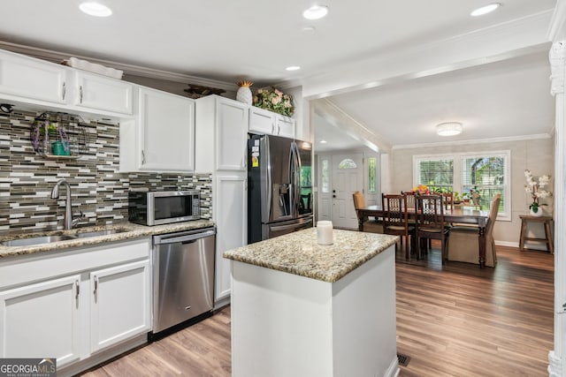 kitchen with light wood-type flooring, appliances with stainless steel finishes, sink, and a kitchen island