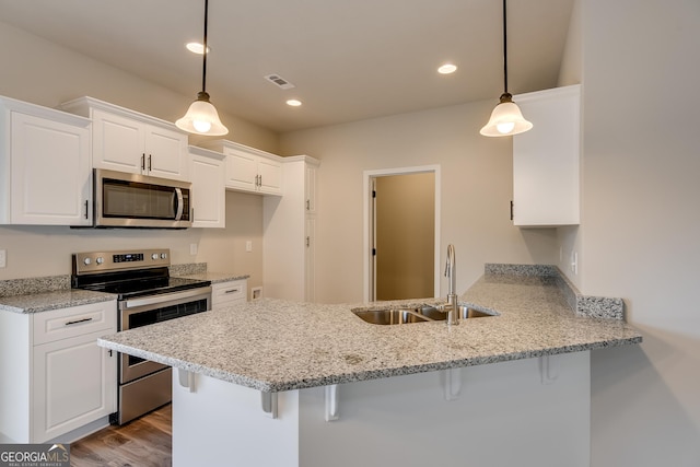 kitchen with pendant lighting, sink, white cabinets, kitchen peninsula, and stainless steel appliances