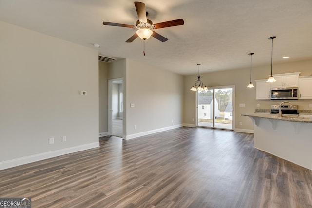 unfurnished living room featuring dark wood-type flooring, sink, and ceiling fan with notable chandelier