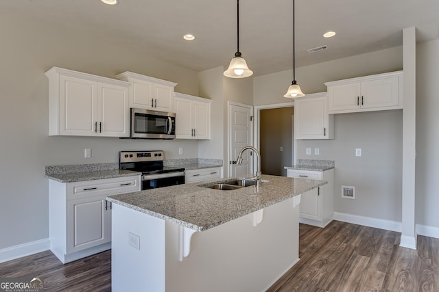 kitchen with white cabinetry, a center island with sink, light stone counters, and stainless steel appliances