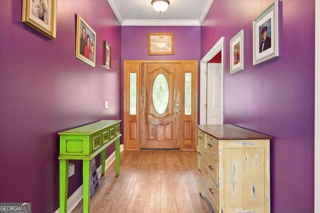 foyer entrance with ornamental molding and light wood-style flooring