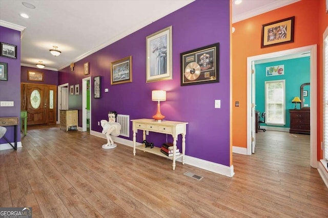 entryway featuring baseboards, light wood-style flooring, visible vents, and crown molding