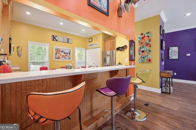 bar featuring visible vents, baseboards, ornamental molding, stainless steel refrigerator with ice dispenser, and dark wood-style floors