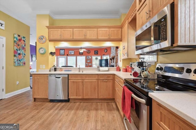 kitchen with stainless steel appliances, light wood-style flooring, ornamental molding, a sink, and a peninsula