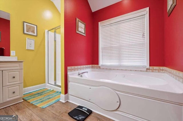 bathroom featuring baseboards, wood finished floors, vanity, a shower stall, and a bath