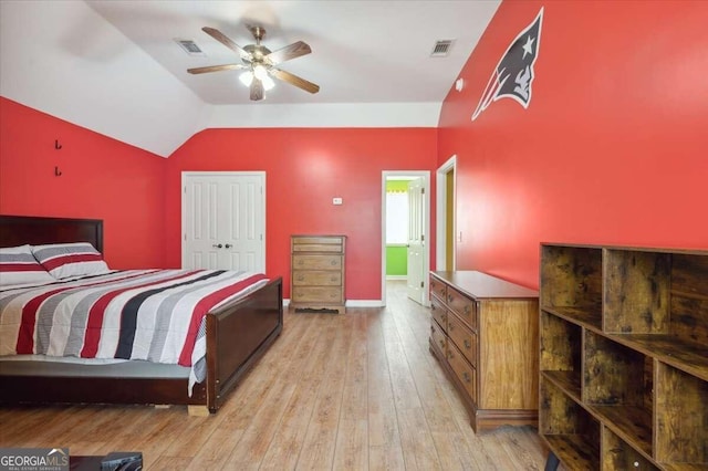 bedroom with lofted ceiling, light wood finished floors, visible vents, and a closet