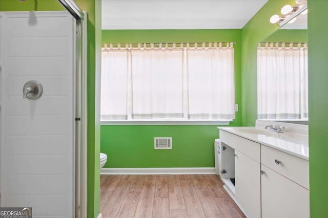 bathroom with wood finished floors, plenty of natural light, vanity, and visible vents