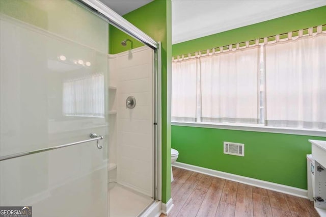 bathroom featuring toilet, wood finished floors, a shower stall, and visible vents