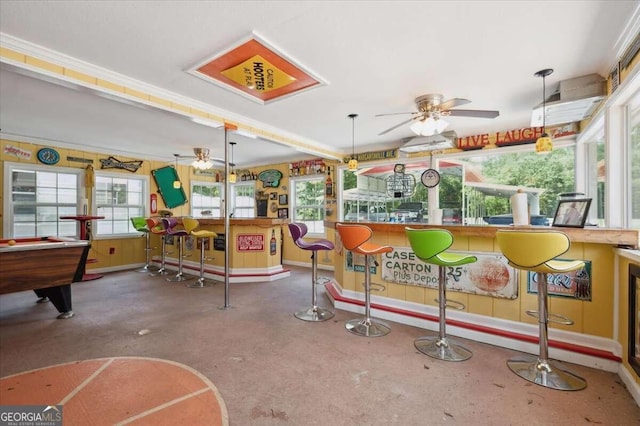 recreation room with a bar, a wealth of natural light, and a ceiling fan