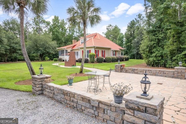 back of property featuring a chimney, a lawn, and a patio area