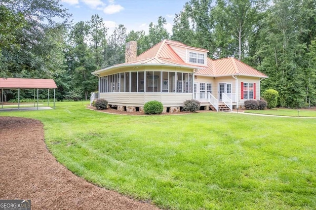 view of front of home with a sunroom, a chimney, metal roof, a standing seam roof, and a front yard