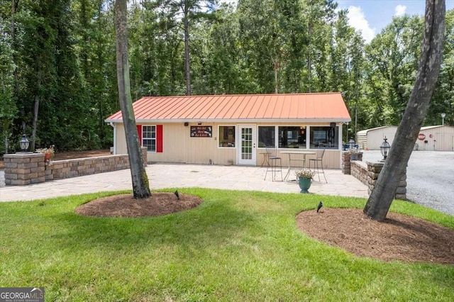 back of property featuring a yard, a standing seam roof, a patio, and metal roof