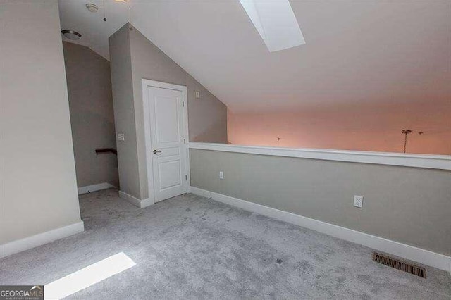 bonus room featuring lofted ceiling with skylight and light colored carpet