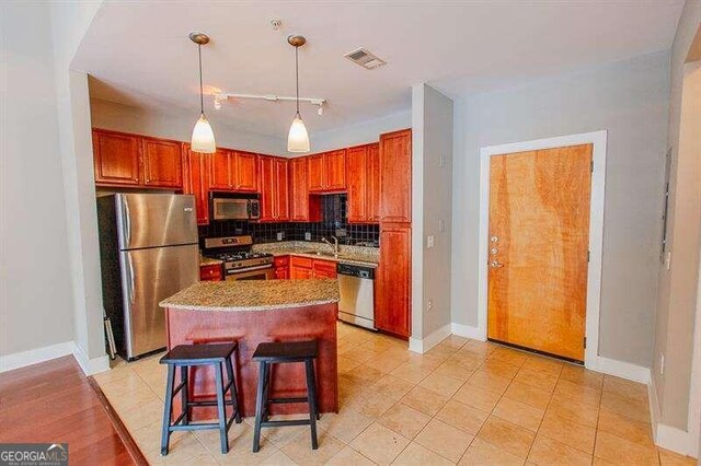 kitchen with light tile patterned floors, backsplash, stainless steel appliances, hanging light fixtures, and sink