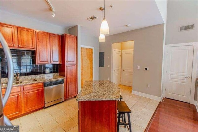 kitchen featuring dishwasher, backsplash, light stone counters, track lighting, and pendant lighting