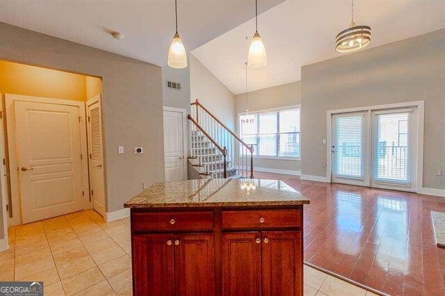 kitchen with light hardwood / wood-style flooring, a center island, a wealth of natural light, and light stone countertops