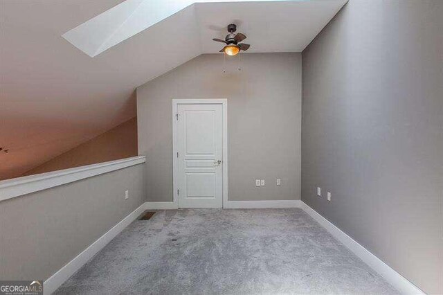 additional living space featuring carpet floors, ceiling fan, and vaulted ceiling with skylight