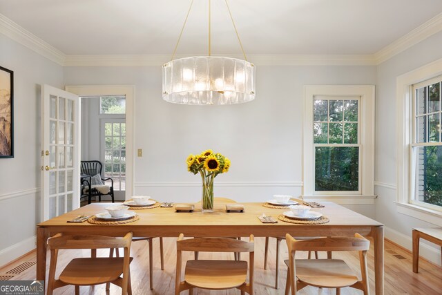 dining area featuring ornamental molding, an inviting chandelier, a wealth of natural light, and light wood-type flooring