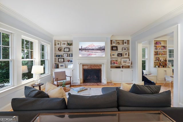 living room featuring built in shelves, a premium fireplace, crown molding, and hardwood / wood-style floors