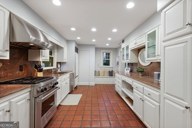 kitchen with white cabinetry, decorative backsplash, wall chimney range hood, and stainless steel appliances