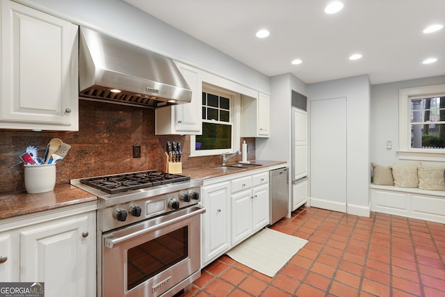 kitchen featuring white cabinets, backsplash, appliances with stainless steel finishes, and wall chimney exhaust hood