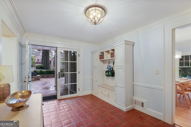 entryway featuring an inviting chandelier, crown molding, and tile patterned flooring