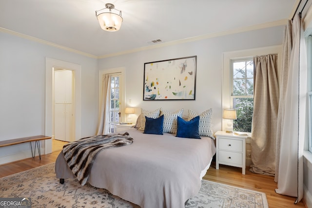 bedroom with light hardwood / wood-style flooring and crown molding