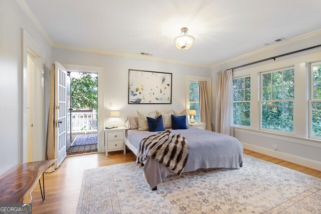 bedroom with light hardwood / wood-style floors, ornamental molding, multiple windows, and access to outside