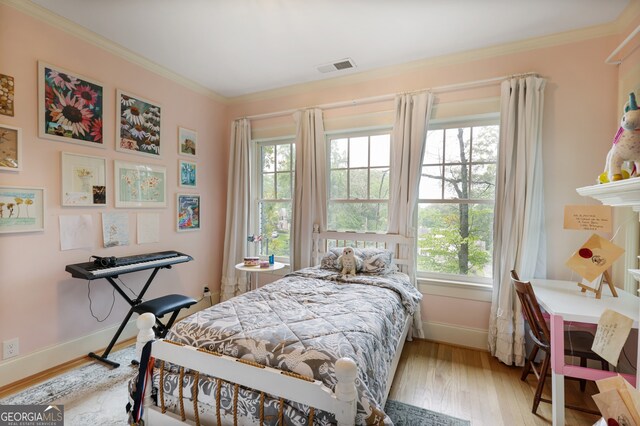 bedroom with crown molding, multiple windows, and light wood-type flooring