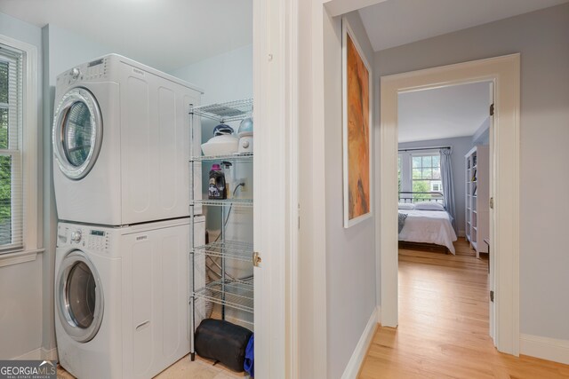 clothes washing area featuring stacked washer / dryer and light wood-type flooring