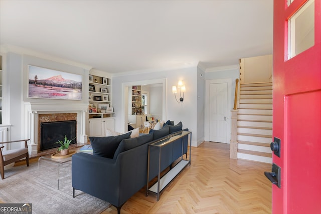 living room featuring crown molding, built in features, light parquet flooring, and a high end fireplace