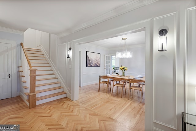 interior space featuring an inviting chandelier, light parquet flooring, and ornamental molding