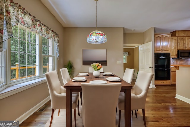 dining room featuring dark wood-style flooring, visible vents, and baseboards