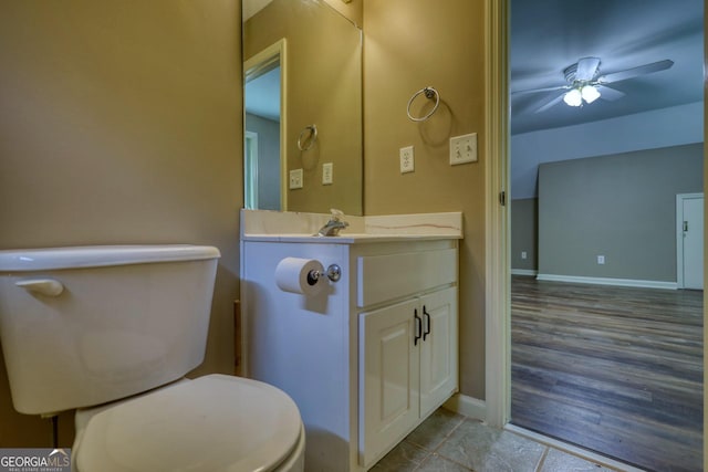 bathroom with toilet, ceiling fan, baseboards, and vanity