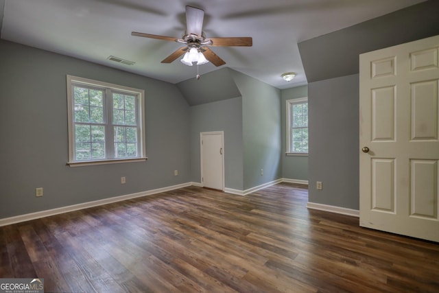 unfurnished bedroom featuring dark wood-type flooring, visible vents, vaulted ceiling, and baseboards