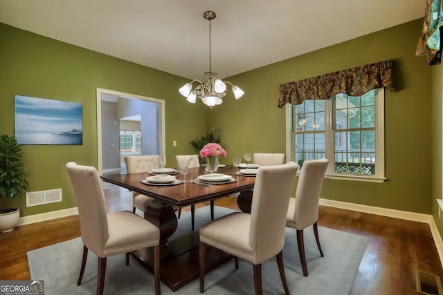 dining room featuring dark wood-style floors, visible vents, baseboards, and an inviting chandelier