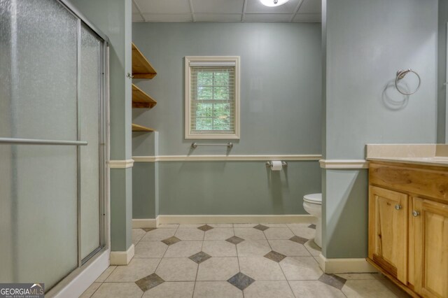 bathroom featuring vanity, tile patterned flooring, toilet, and a drop ceiling